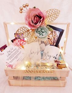 an open wooden box filled with cards and other items that include a pink flower on top