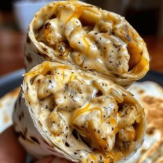 two burritos with cheese and sauce on them are held up in the air