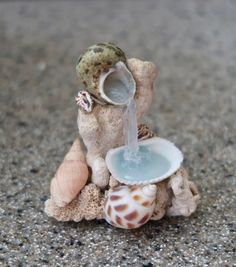 there is a small statue of a giraffe drinking water from a bowl with seashells around it