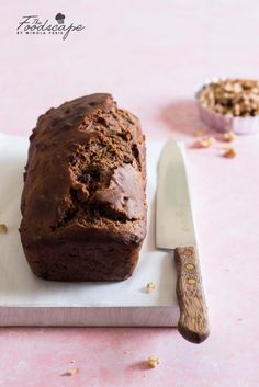 a loaf of chocolate bread sitting on top of a cutting board next to a knife