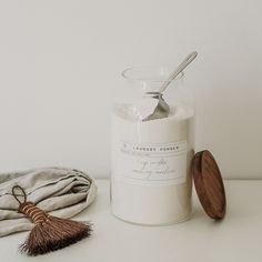 a white jar with a wooden lid and a tassel on the table next to it