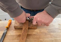 a person using a pair of scissors to cut wood with a carving tool on a wooden cutting board