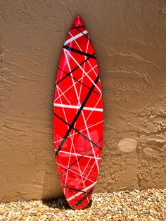 a red surfboard leaning against a brown wall