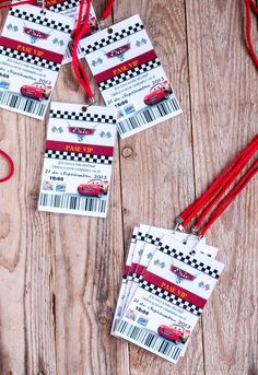 four race car birthday party tags with red string and tassels on wooden table