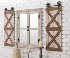 a white brick wall with two mirrors on it and a candle next to the mirror