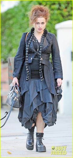 a woman in black dress and boots walking down the street