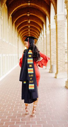 a woman in graduation gown and cap walking down a hallway with arches on both sides