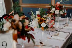 the table is set with wine glasses and floral centerpieces on top of it