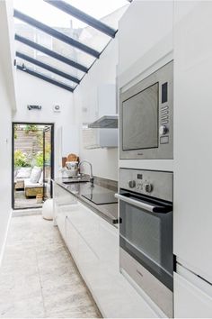 a kitchen with an oven, microwave and sink under a skylight that is open to the outside