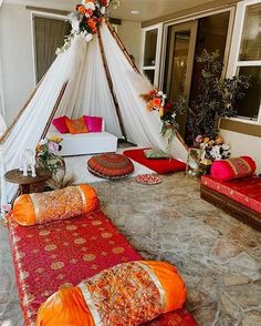 a teepee tent set up with pillows and blankets on the ground in front of it