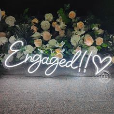 an illuminated sign that says engaged surrounded by flowers