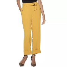 a woman in yellow pants and heels is standing with her hands behind her back to the camera