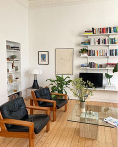 a living room filled with furniture and bookshelves next to a glass coffee table