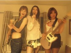 three young women standing next to each other holding guitars