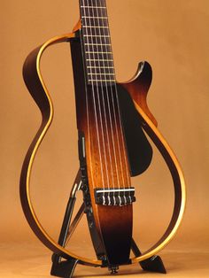 an acoustic guitar is on display in front of a brown background and has a wooden stand holding it