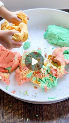 someone is decorating some food on a white plate with green and pink frosting