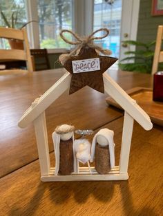 a small wooden house with a star on the roof and two white snowmen in it