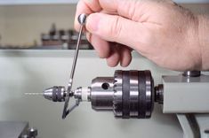 a person using a driller to cut metal parts on a machine with holes in the center