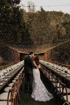 a bride and groom standing in front of a long table