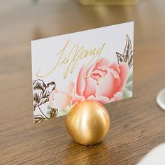 there is a gold ball on the table with a card in it's holder