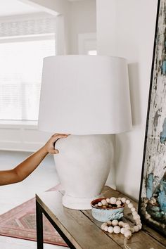 a woman holding a white lamp over a table