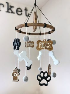 a dog themed mobile hanging from the ceiling in a child's room with name tags and paw prints