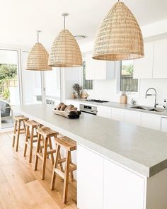 a kitchen with white cabinets and wooden stools in front of an island counter top