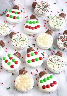 frosted cupcakes decorated like snowmen on a white table with sprinkles