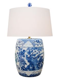 a blue and white vase with a light on it's side next to a lamp