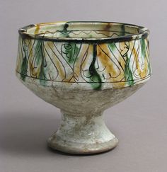 a white bowl with green and yellow designs on the rim, sitting on a gray surface