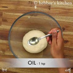 a person is spooning oil into a doughnut in a glass bowl on top of a wooden table