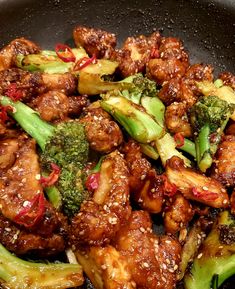 chicken and broccoli stir fry in a wok with sesame seeds on top