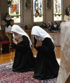 two women dressed in black sitting on the floor next to each other with their hands together