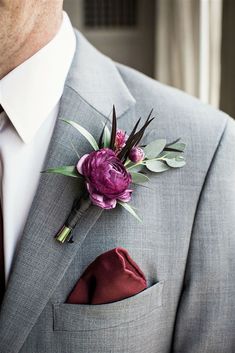 a man in a gray suit with a red tie and flower boutonniere