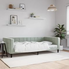 a white living room with a green couch and some shelves on the wall above it