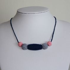 a white mannequin with a blue and pink crochet necklace on it