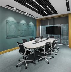 an empty conference room with a large white table and black chairs in front of a projection screen