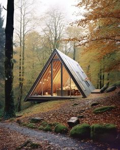 a small cabin in the woods surrounded by trees and leaves, with its roof made out of