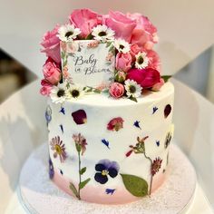 a baby in bloom cake with pink and white flowers on the top, sitting on a table