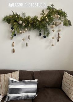 a couch with christmas decorations hanging on the wall above it and a striped pillow below