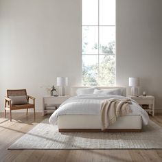 a bedroom with white walls and wooden flooring has a large bed in the middle