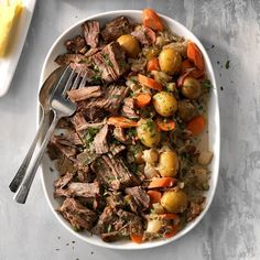 a white bowl filled with meat, potatoes and carrots on top of a table