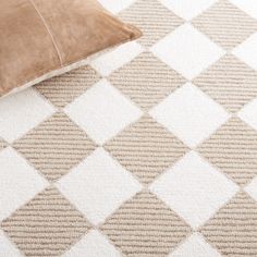 a brown pillow sitting on top of a white and beige rug next to a cushion