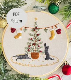 a cross stitch christmas tree with two cats hanging from it