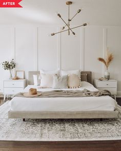 a bedroom with white walls and wooden flooring, a chandelier above the bed