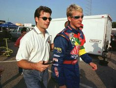 two men standing next to each other in a parking lot