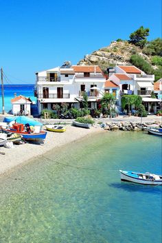 several boats are parked on the beach in front of some white buildings and blue water