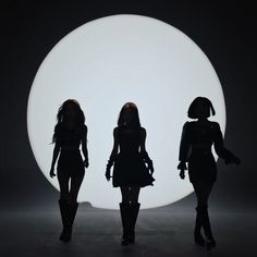 three women walking in front of a white circle