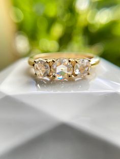 three stone ring sitting on top of a white surface