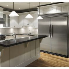 a kitchen with white cabinets and stainless steel appliances in the center, along with an island